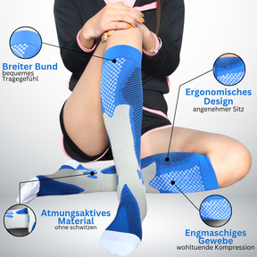 Eine Person in blauen und grauen kniehohen Tieberg™️ Spezial Kompressionsstrümpfen sitzt im Schneidersitz, mit vier gekennzeichneten Merkmalen: breites Band, atmungsaktives Material, ergonomisches Design und engmaschiges Gewebe für Kompressionstechnologie.